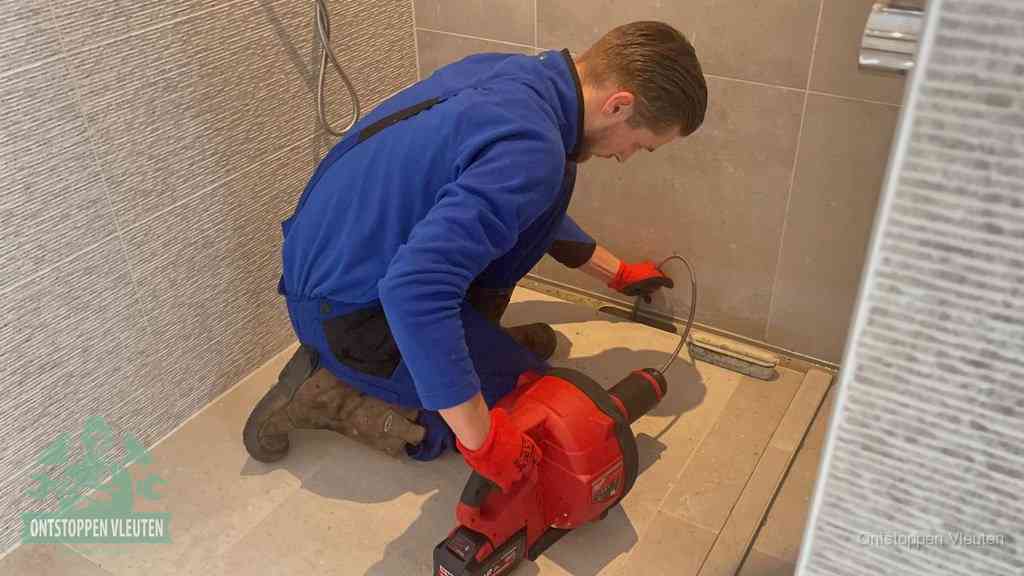 Een monteur ontstopt een langwerpige douchegoot met een elektrische veer, een doucheputje verstopt door haren en zeep in Vleuten
