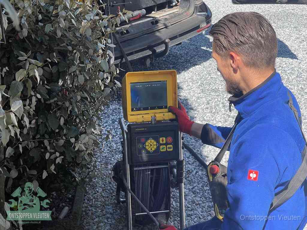 Een monteur bedient een rioolinspectiecamera met monitor en haspel om de verstopping in beeld te brengen in Vleuten