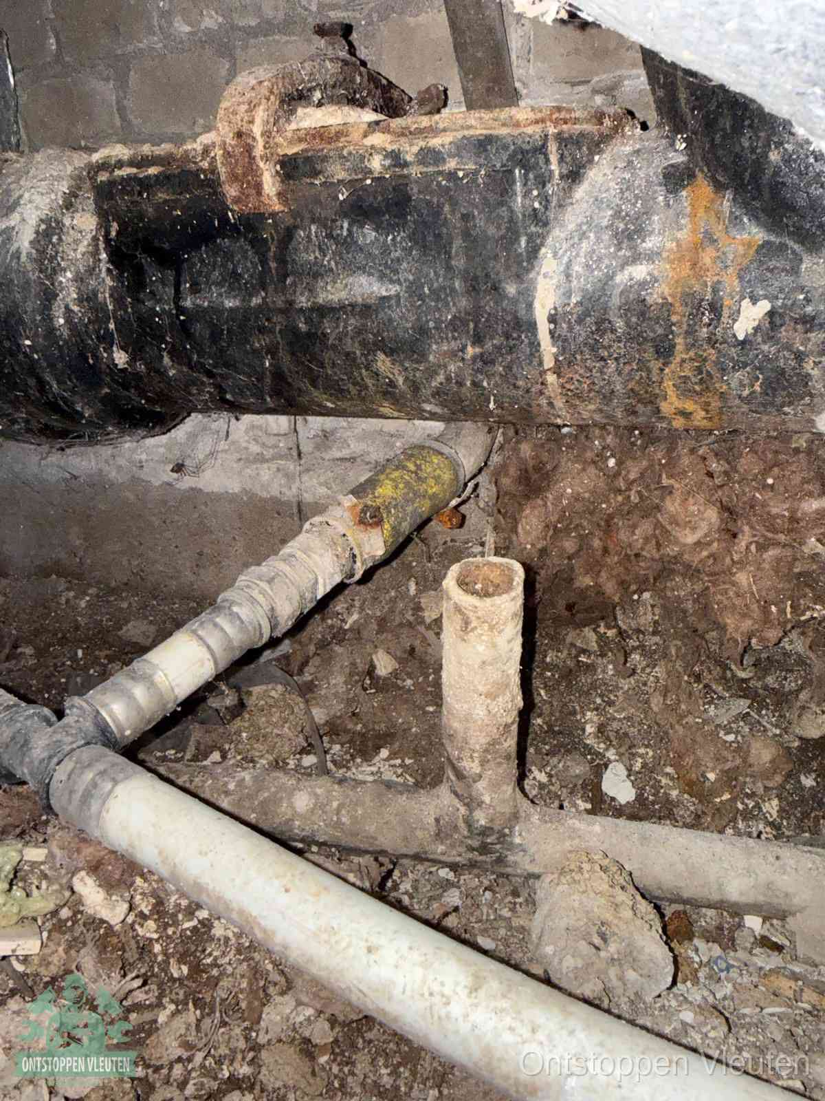 Een oude hoofdrioolbuis met roest- en kalkaanslag in een kruipruimte, oorzaak van terugkerende structurele rioolproblemen in Vleuten